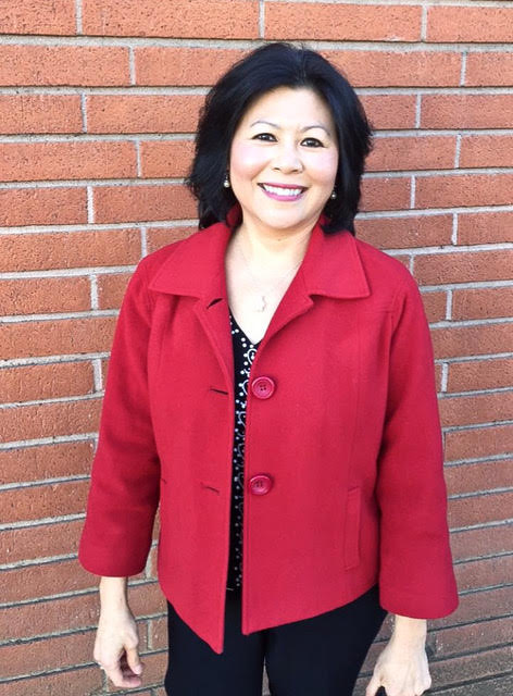 Woman stands wearing a red coat and black pants