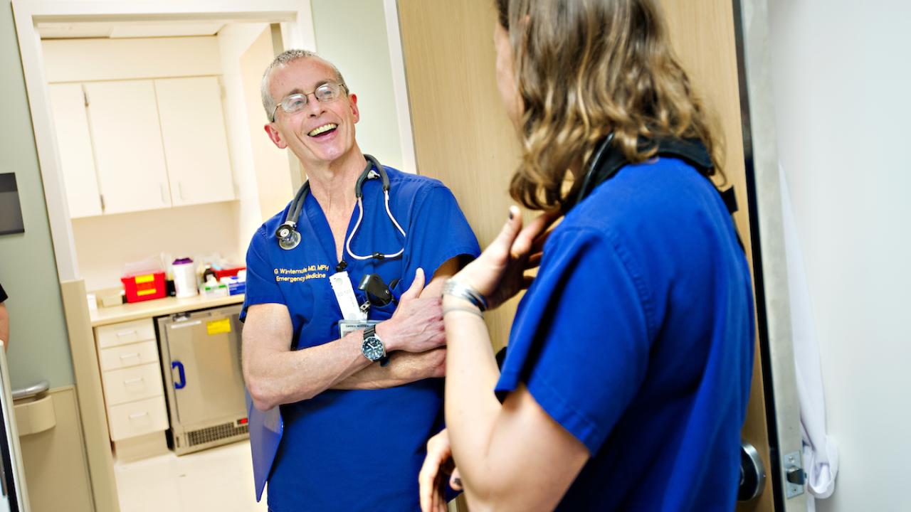 Two medical professionals in blue scrubs conversing in a hospital