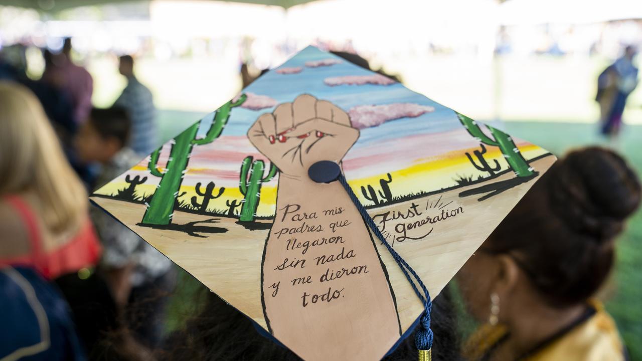Decorated graduation cap with a fist and the words "para mis padres que Negaron sin nada y me dieron todo. First Generation"