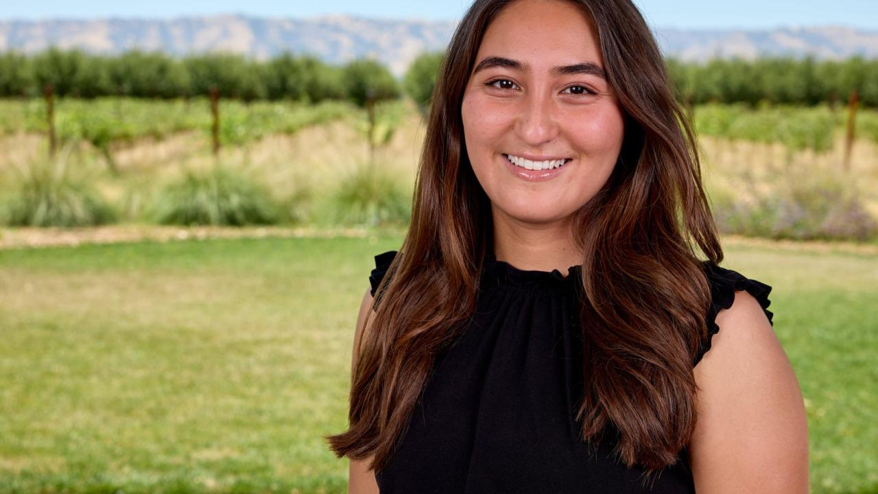 Marisa Davidson in black top with green field background.