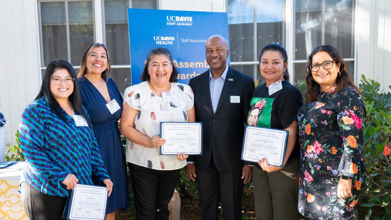 Five women stand with Chancellor May holding certificates.