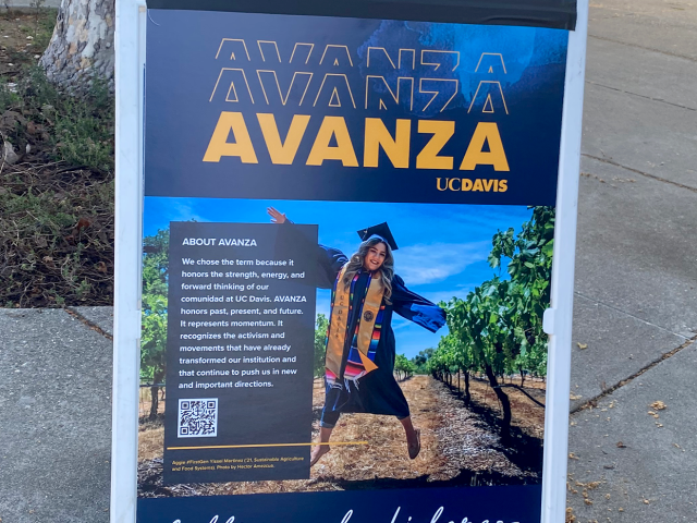 A poster on a board with an image of a female graduate student jumping and the words "AVANZA: cultivando líderes."