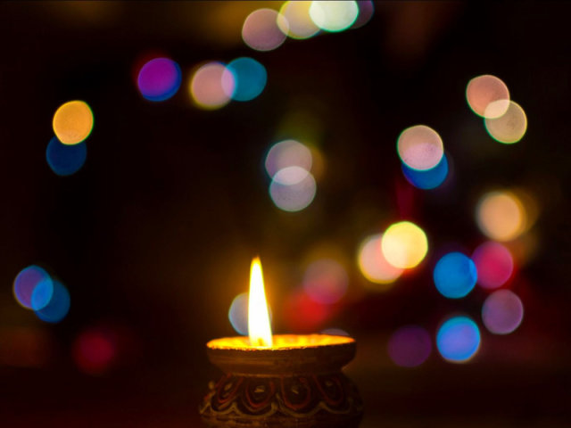Soft colored lights on a dark background with a single lit candle