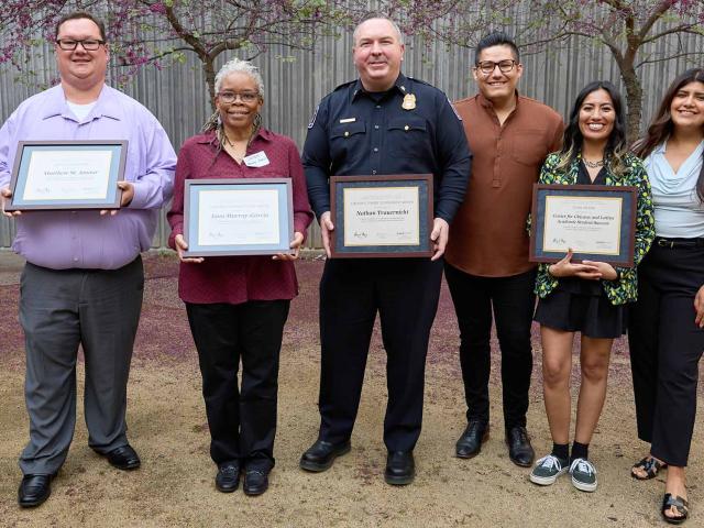 six people stand together holding certificates to show receiving Soaring to New Heights award