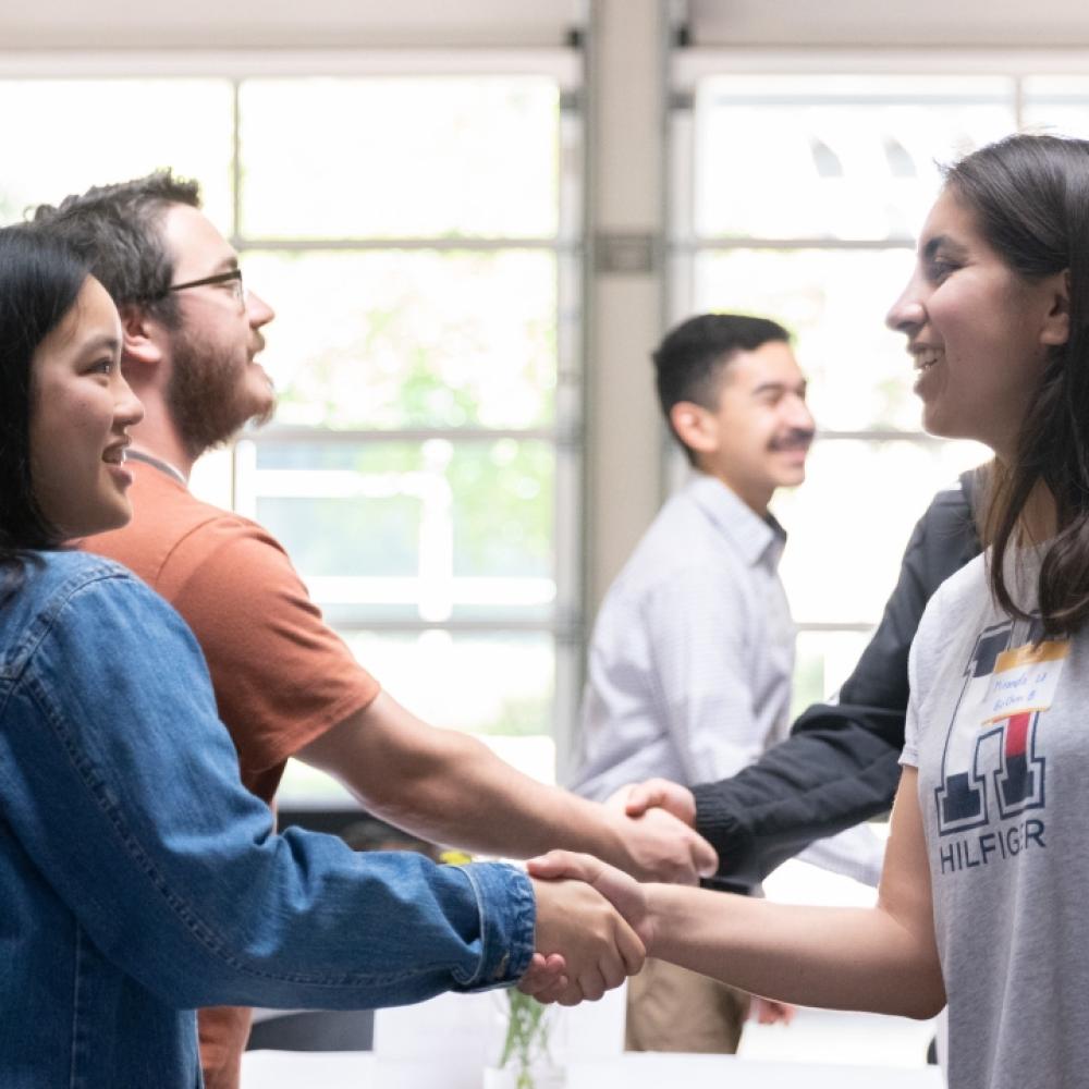 pair of students shake hands in well-lit room