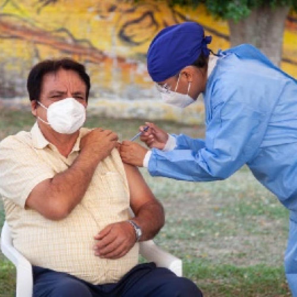 Person receiving a vaccine from a healthcare worker outdoors.