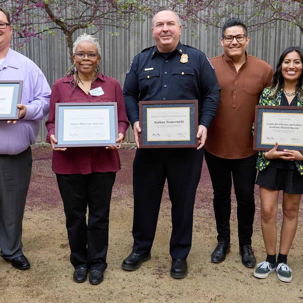six people stand together holding certificates to show receiving Soaring to New Heights award
