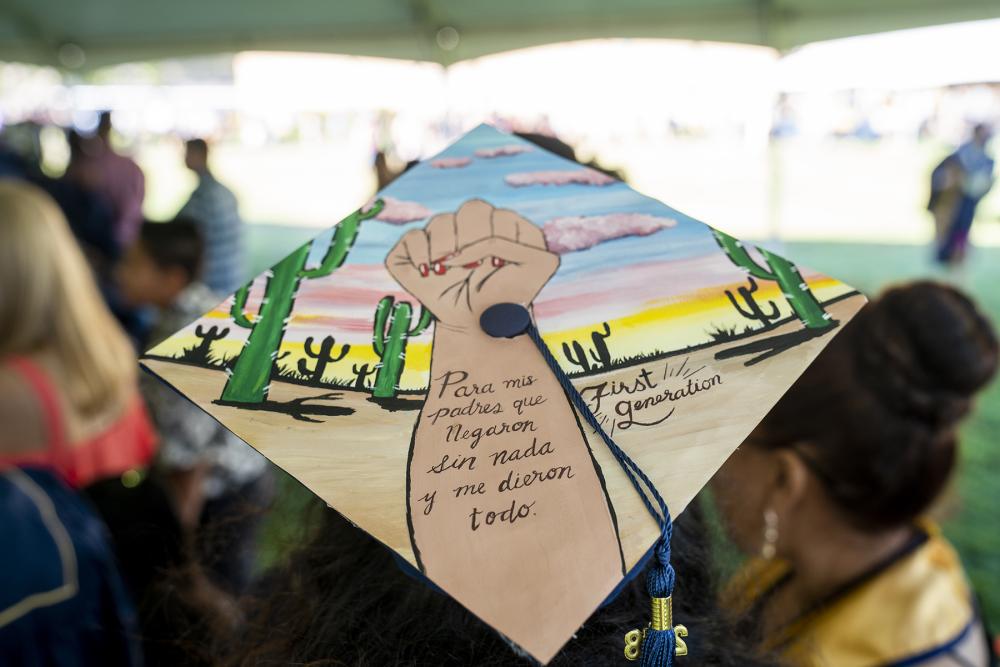 Decorated graduation cap with a fist and the words "para mis padres que Negaron sin nada y me dieron todo. First Generation"