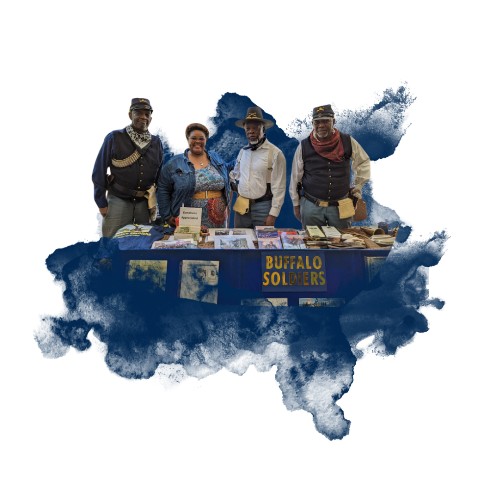 Four people behind a table labeled "BUFFALO SOLDIERS" with historical items displayed.