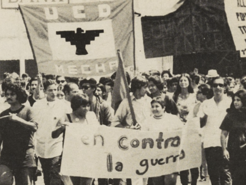 A B&W photo of a group of protestors from the 1960s, holding a banner that says "UCD MECHA" and a sign, "en contra la guerra."