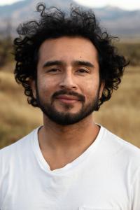 Javier Zamora looks into the camera with a smile and wears a white t-shirt