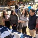 Three female students talk with two male professors at tabling event on UC Davis quad. Another female student is reading a brochure.