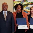 Five people posing with certificates in front of an abstract painting.