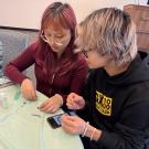 two students sit at table making bracelets at de-stress event