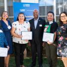 Five women stand with Chancellor May holding certificates.