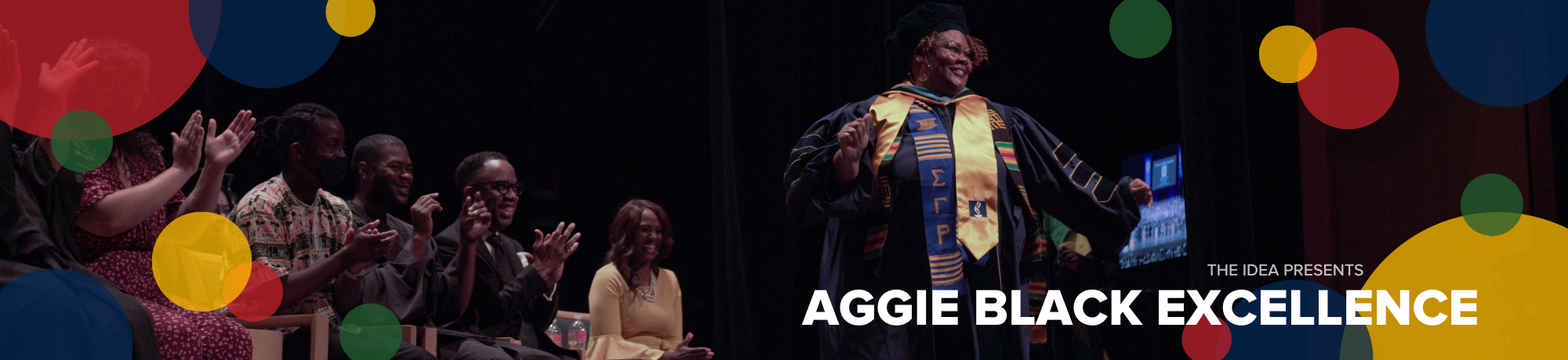 Person in graduation regalia celebrates on stage while seated audience claps; text reads "THE IDEA presents AGGIE BLACK EXCELLENCE."